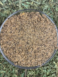 a bowl of brown sand on top of grass